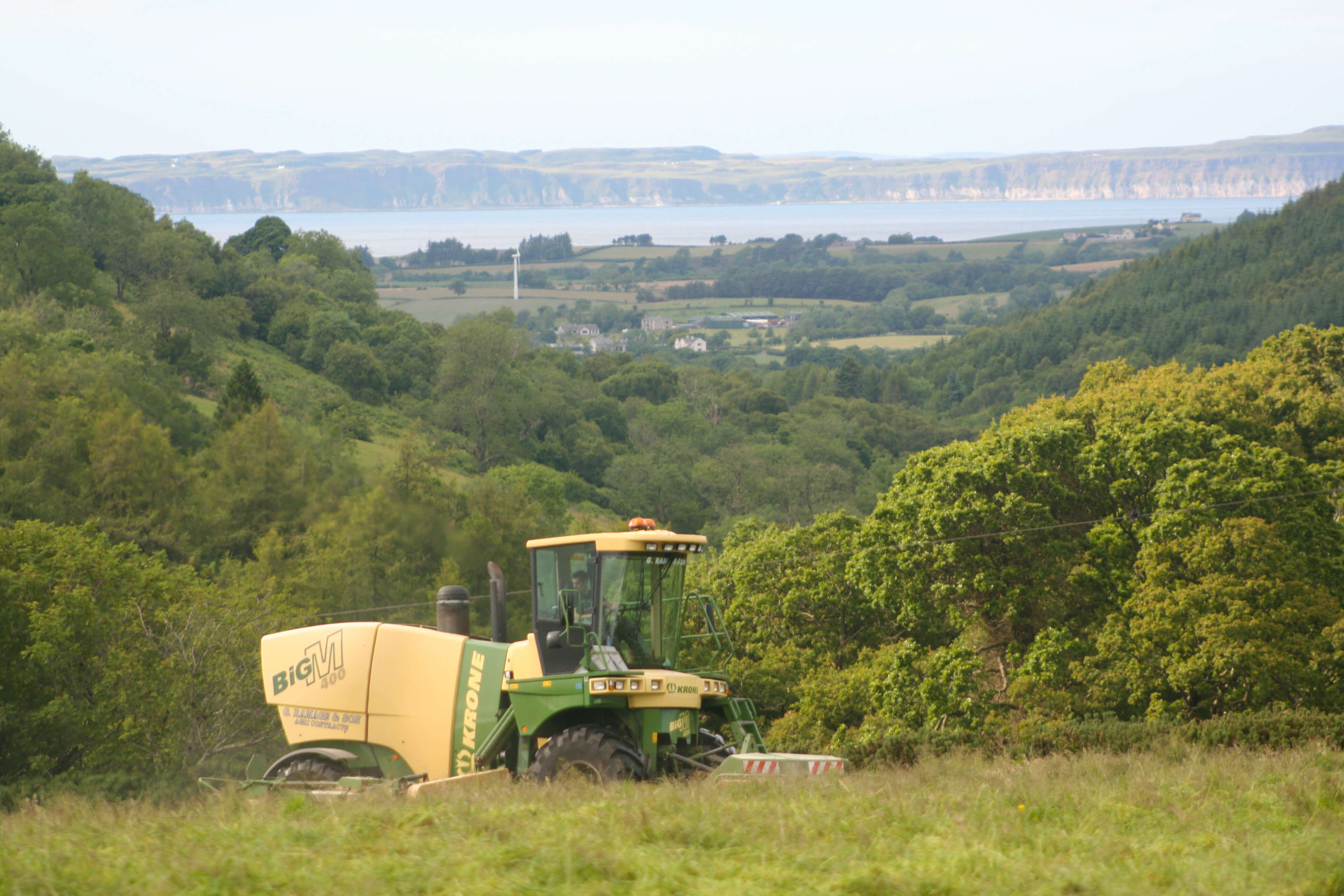 Harvesting At The Hollow, Glenshesk, with the Causeway Coast in the background